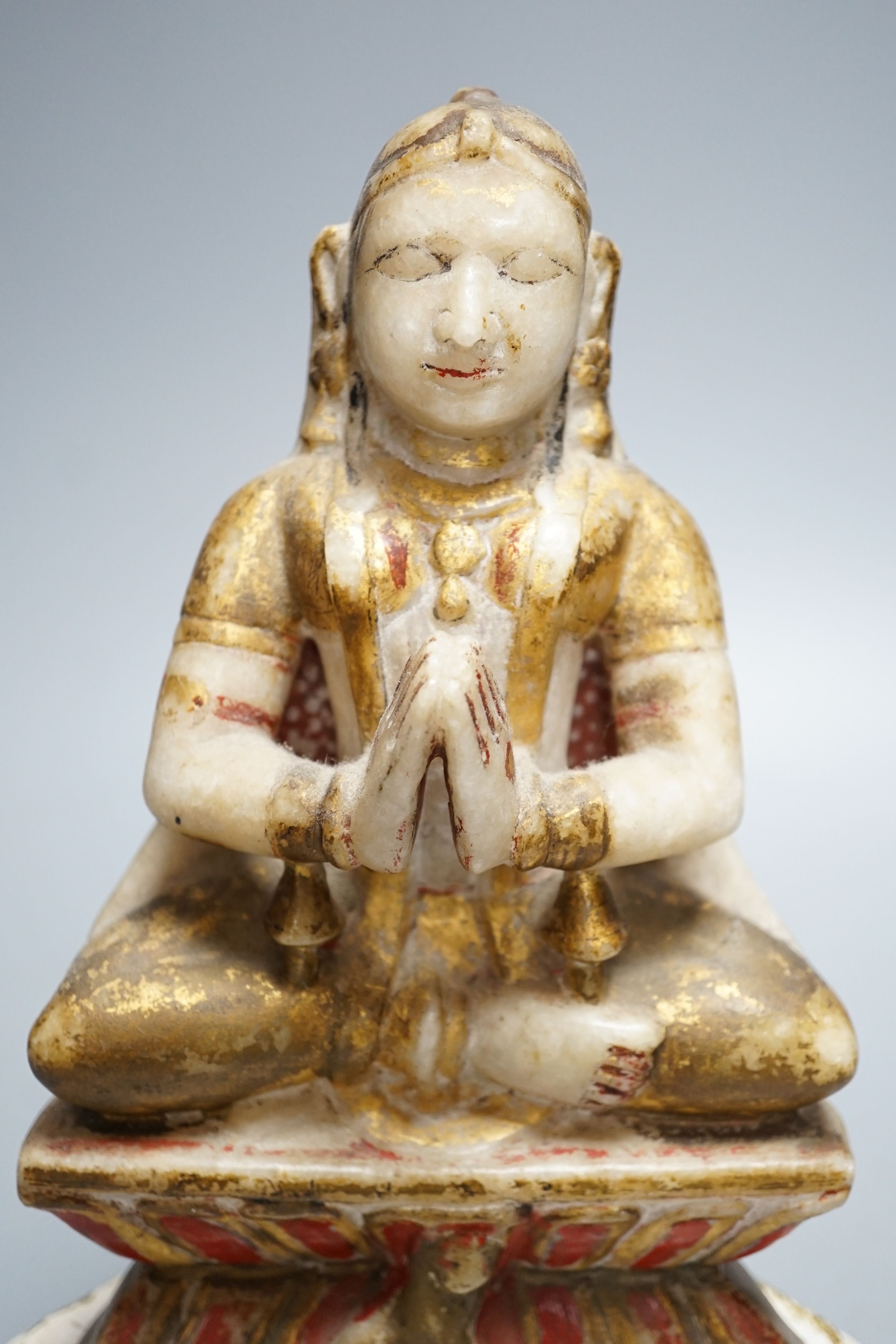 A late 19th century Indian carved alabaster seated figure, on associated wooden stand, 26cm